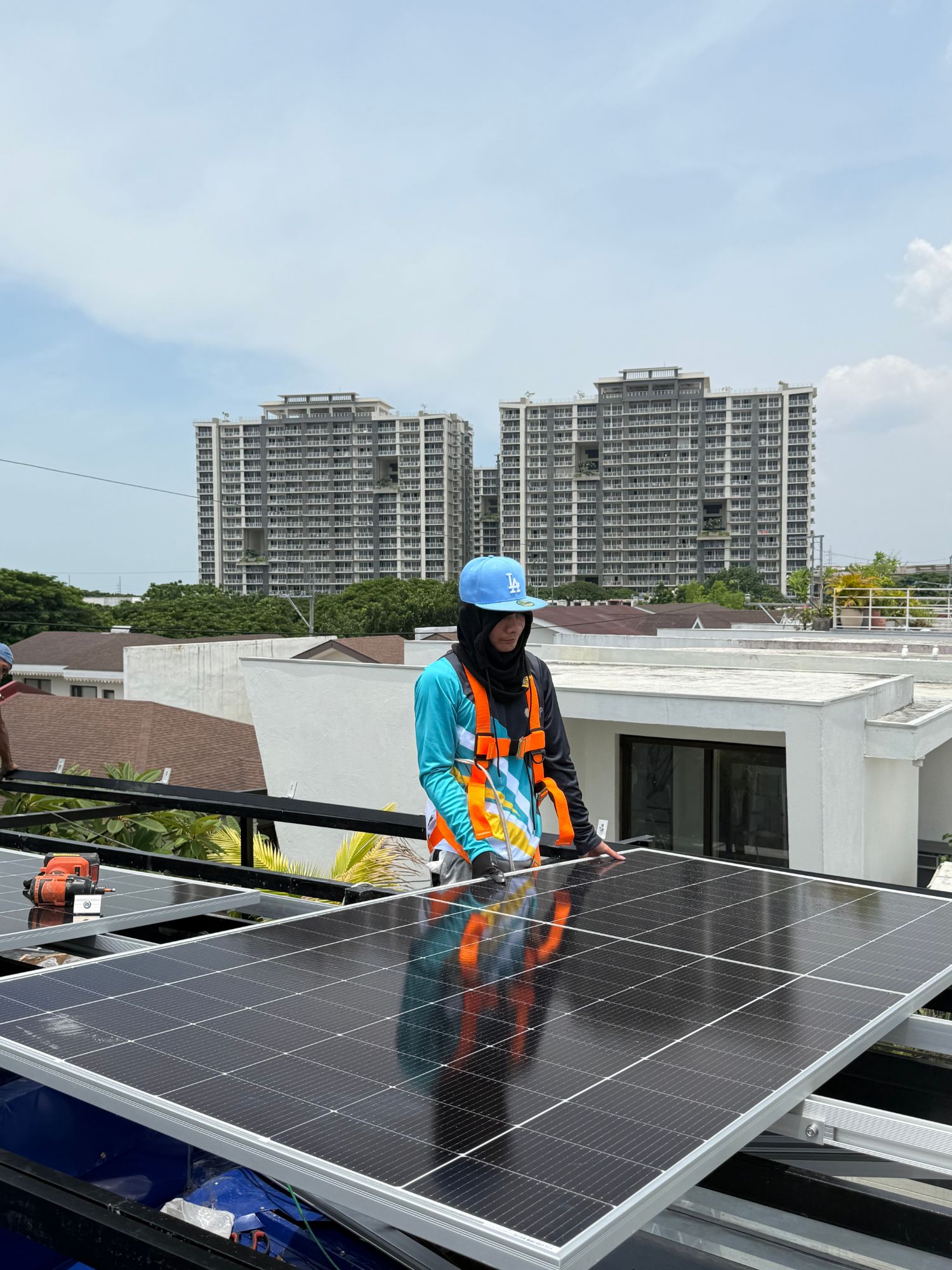 Installer standing on a finished rooftop solar array with condo towers in the background