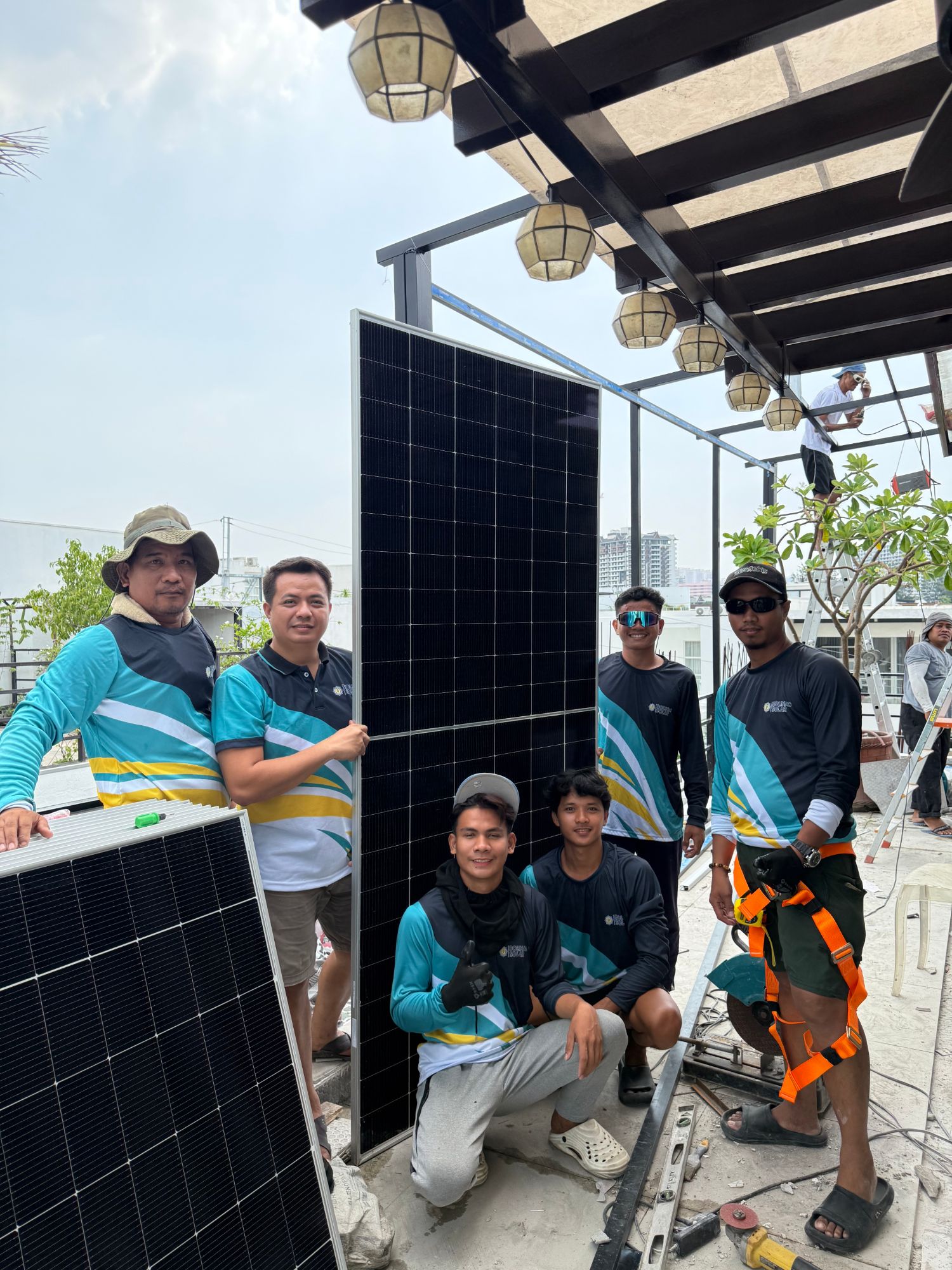 Bolinao Solar installation team with a solar panel on a rooftop