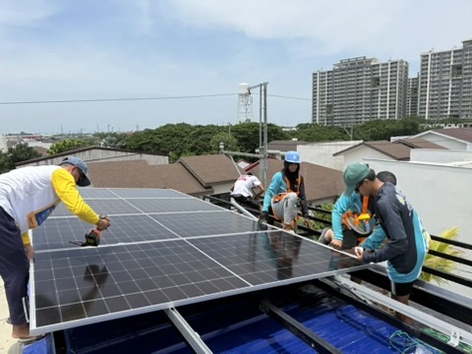 Bolinao Solar crew in safety harnesses fitting solar panels onto a rooftop frame